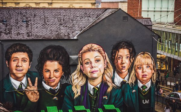 Mural of the Derry Girls (L-R: James, Michelle, Erin, Orla and Clare) in the city centre shopping district near the Derry City Walls. Photo by <a href="https://unsplash.com/@kmitchhodge?utm_source=unsplash&utm_medium=referral&utm_content=creditCopyText">K. Mitch Hodge</a> 