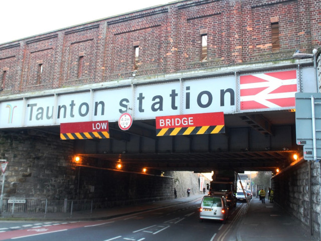 A lorry with a waste container stuck beneath Taunton railway station. Photo: Geof Sheppard @ Wikipedia