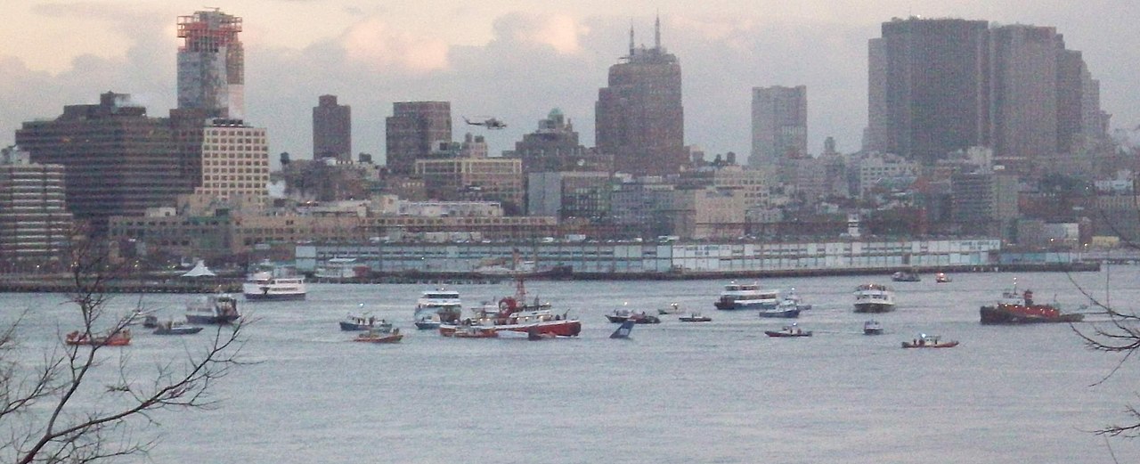 Boats surround the tail of the sunken plane, visible just above the water line. Photo: Izno